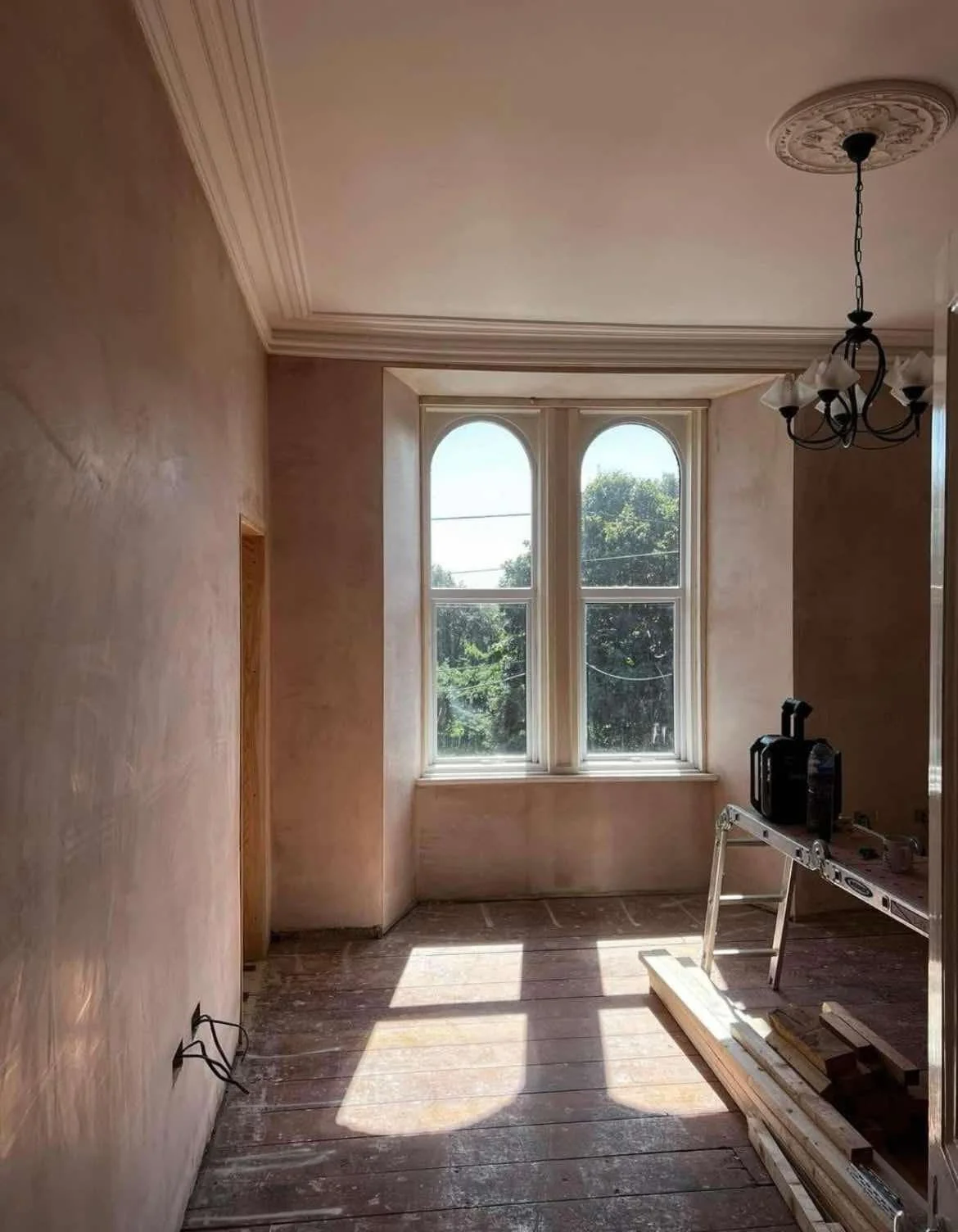 Freshly plastered walls in a period property in Moortown, Leeds, featuring arched windows and decorative ceiling cornicing