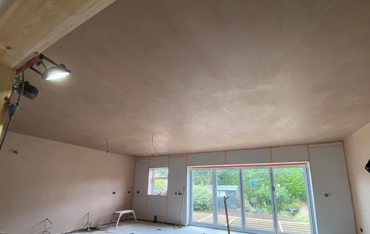 Plastered extension walls and ceiling with exposed plasterboard joints around glazed doors