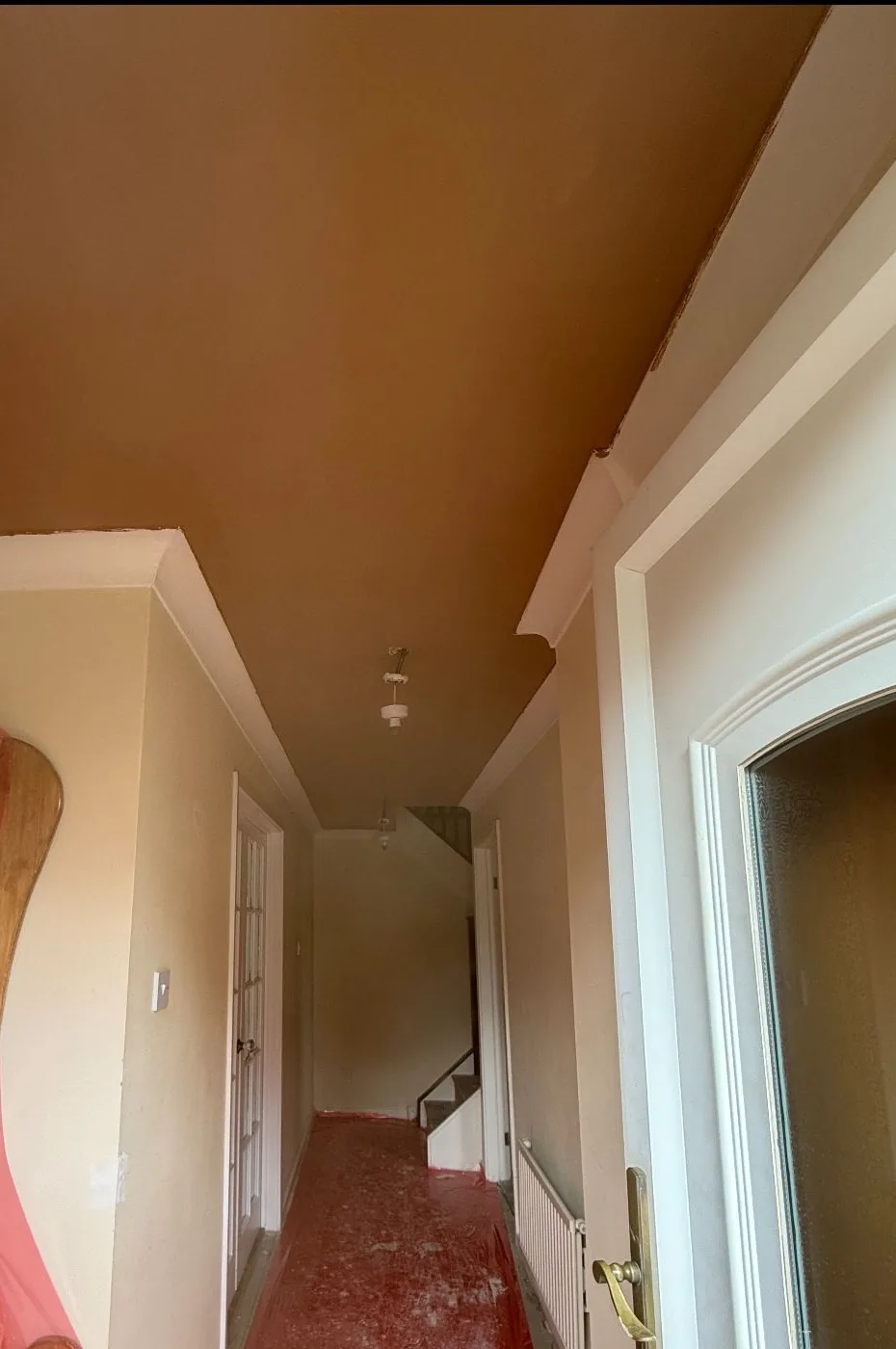 Freshly plastered hallway ceiling with doors and protected flooring below