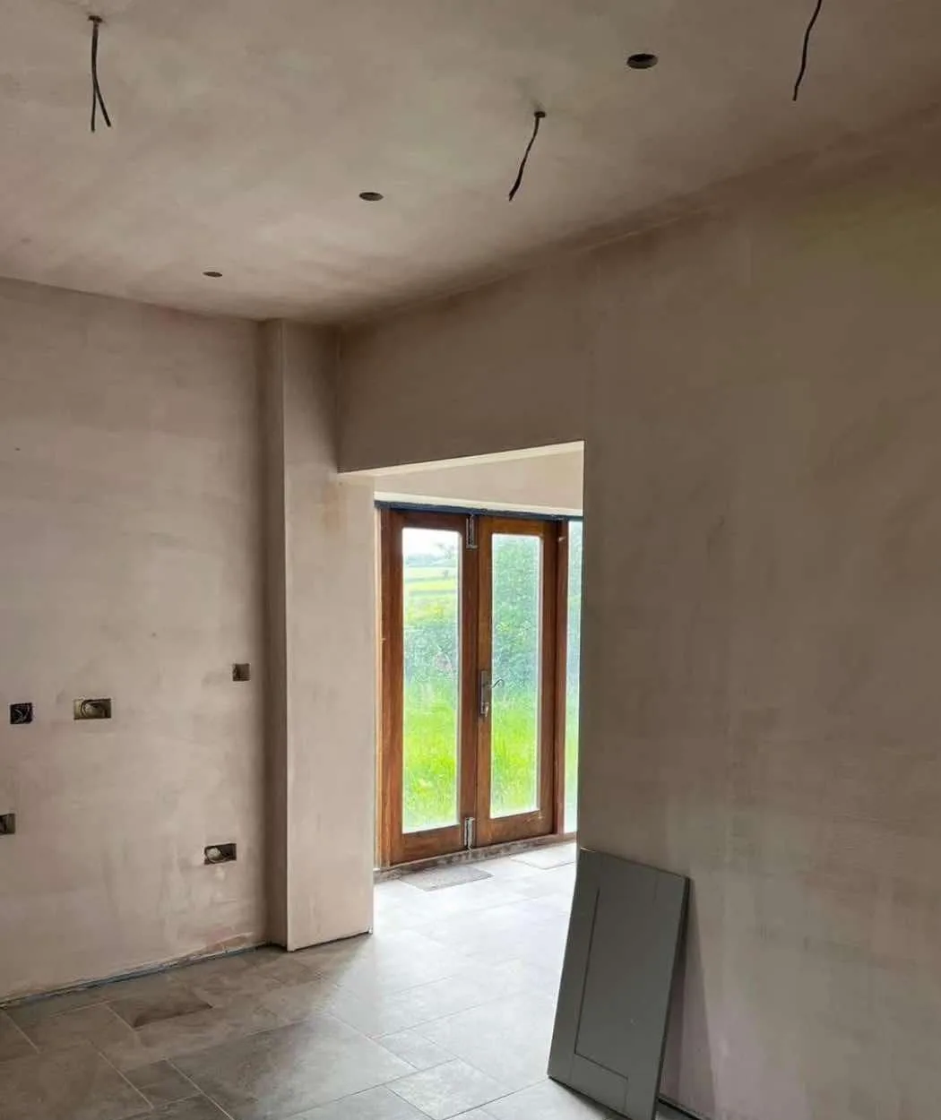 Freshly plastered walls around a doorway with open socket boxes awaiting fittings