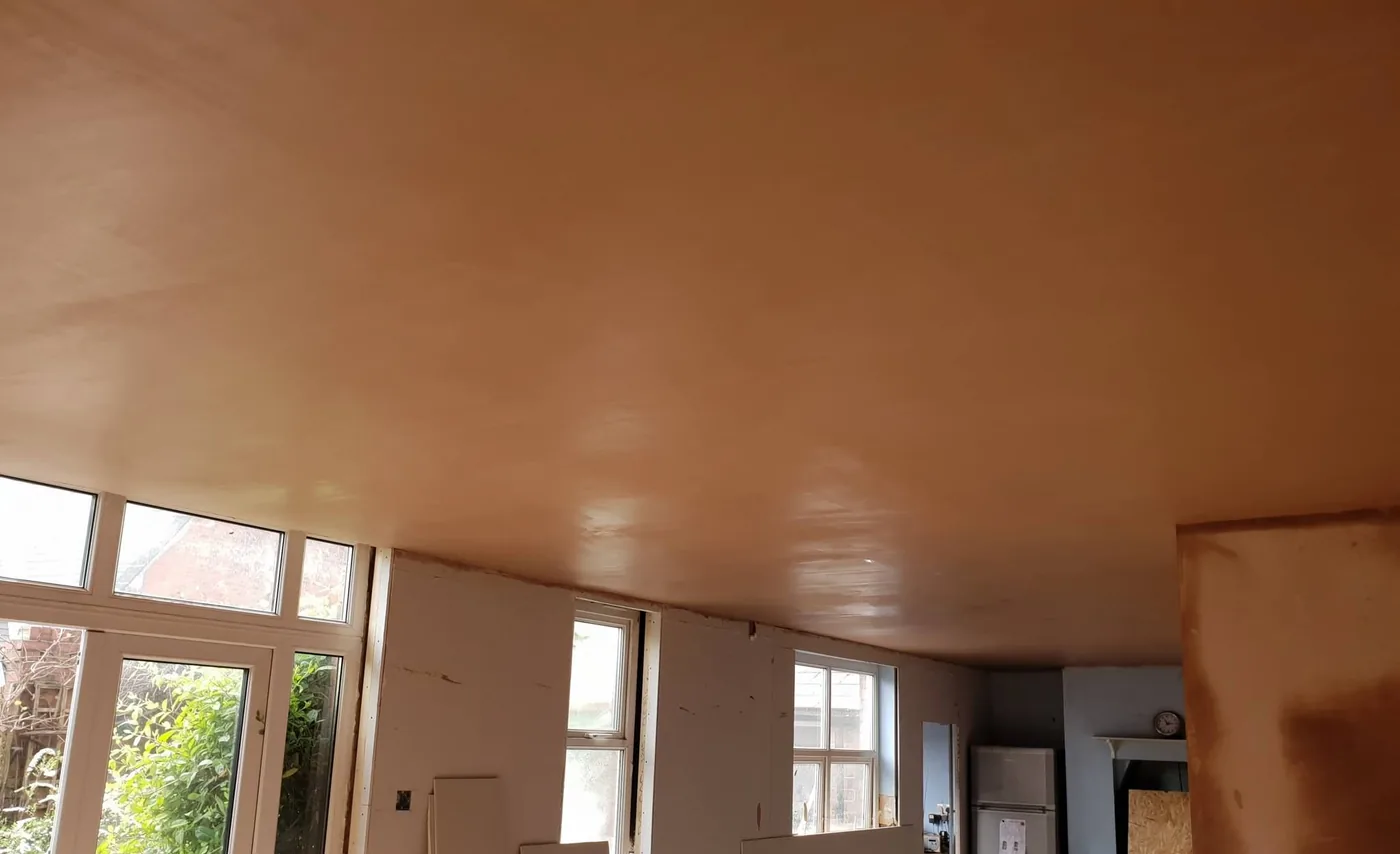 Newly plastered smooth ceiling in a bright room undergoing renovation
